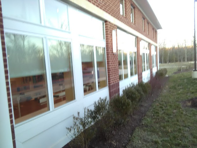 Exterior view of a brick building with large windows and surrounding bushes.
