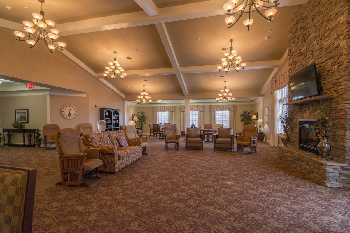 A spacious and elegantly decorated lounge with cozy seating and chandeliers.