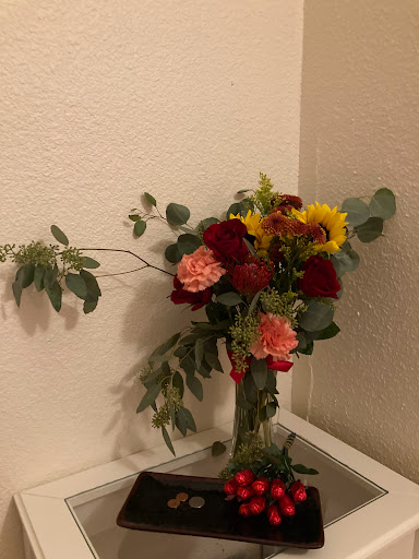 A vibrant bouquet of mixed flowers including sunflowers and roses, elegantly arranged in a vase.