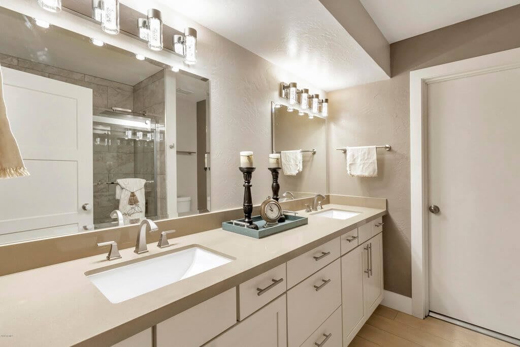 A modern bathroom with double sinks, mirrors, and decorative candles.