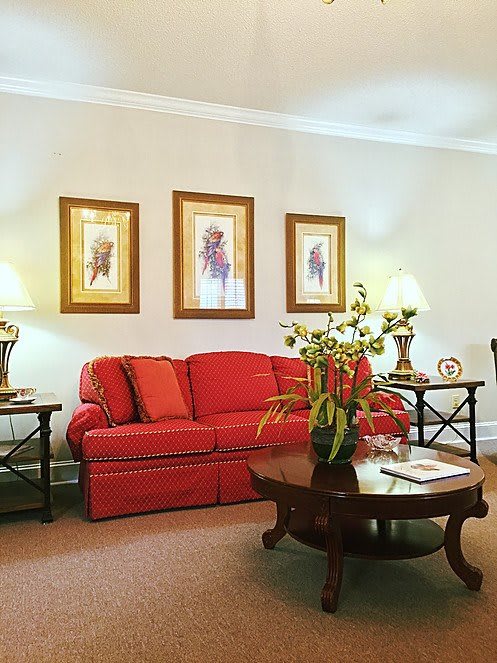 A cozy living room featuring a red sofa, coffee table, and decorative wall art.