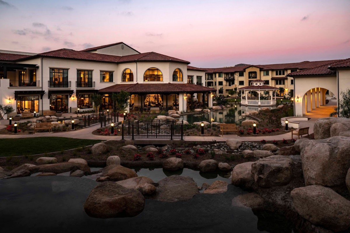 A luxurious resort at sunset with a serene pond in the foreground.
