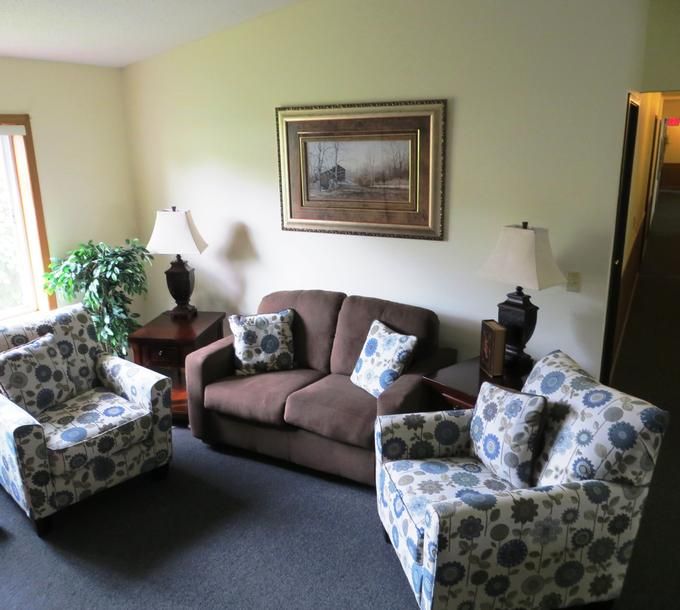 Cozy living room with a sofa, two patterned armchairs, and decorative elements.