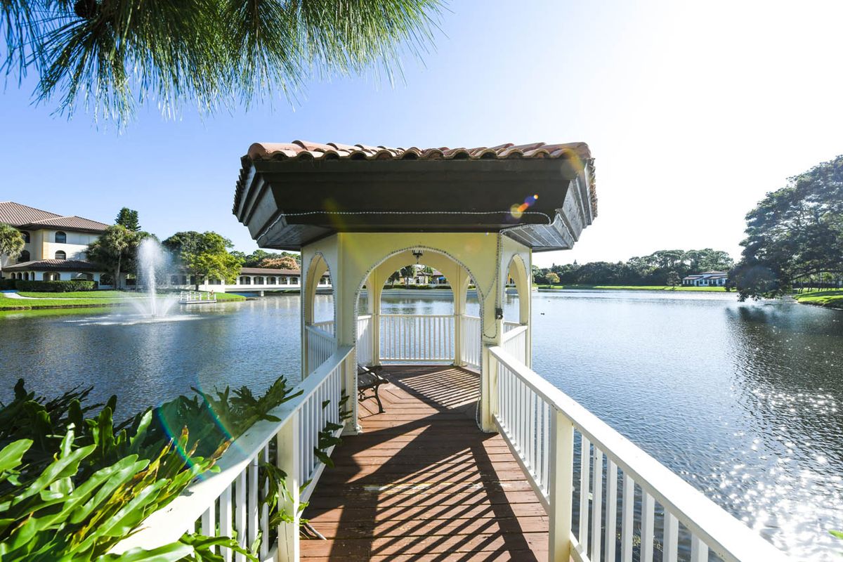 A picturesque gazebo overlooking a serene lake with a wooden walkway.