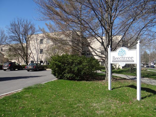 A serene view of a building with a sign, surrounded by lush grass and trees on a clear day.