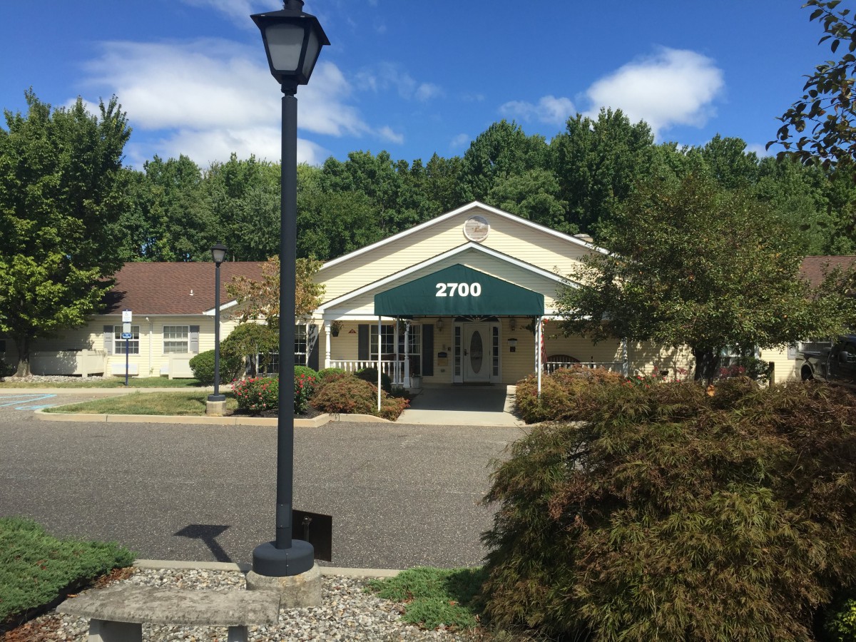 A suburban building with an awning displaying the number 2700, surrounded by trees and a clear sky.