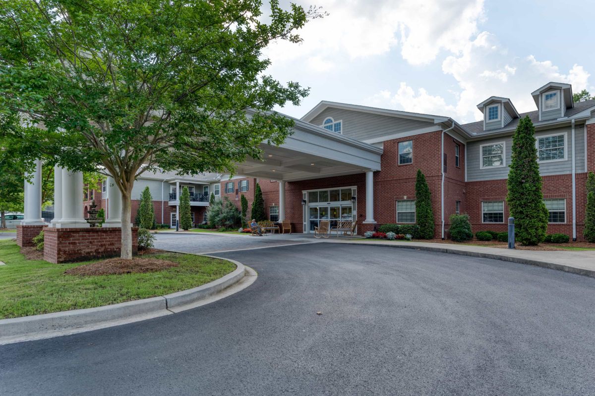 A well-maintained building with a driveway and landscaped surroundings on a cloudy day.