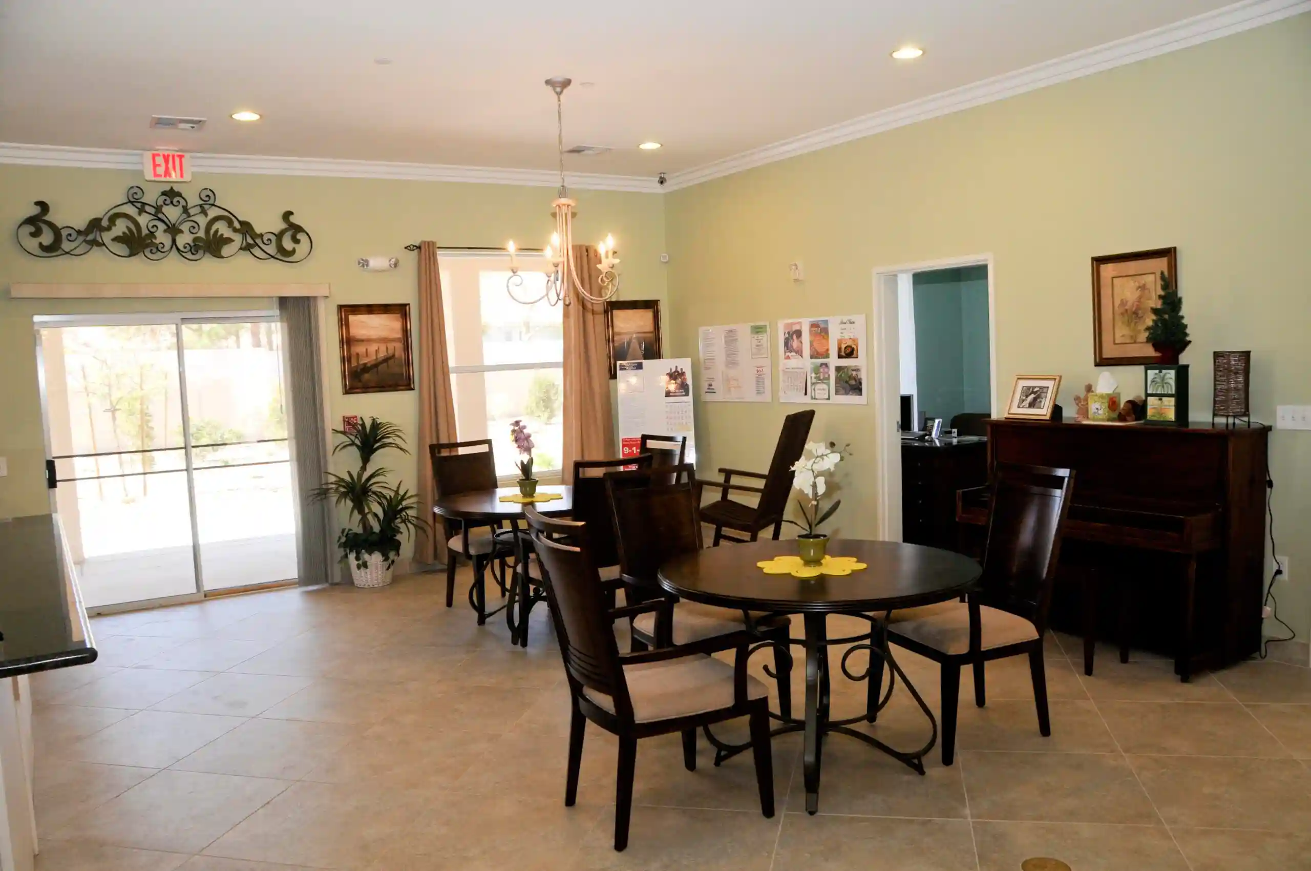 A cozy dining area with multiple tables and chairs, decorated with plants and wall art.