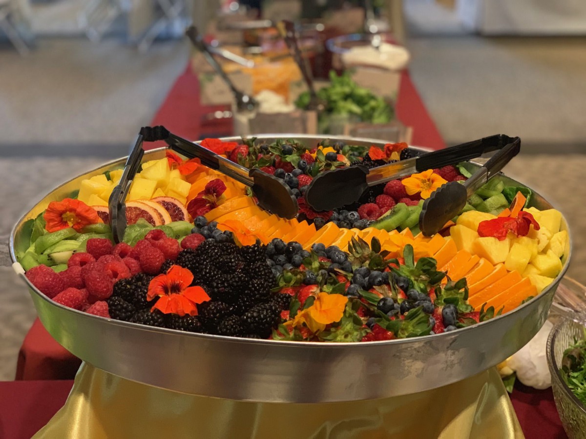 A vibrant fruit platter featuring an assortment of berries and sliced fruits at a buffet.