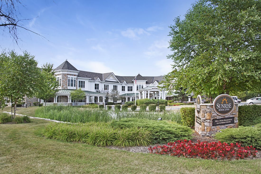 A luxurious mansion with beautiful landscaping and a pond in the foreground.