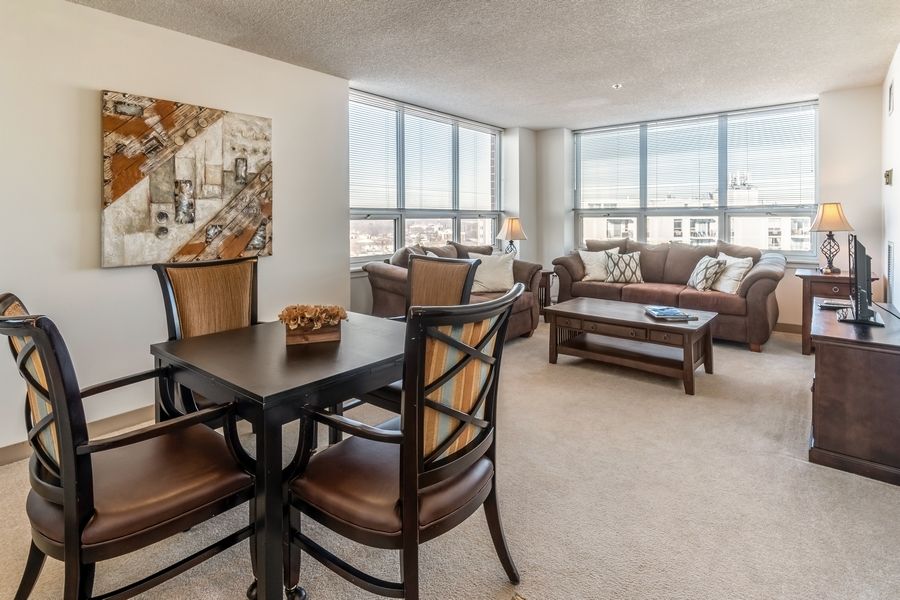 A spacious living and dining area with large windows, elegant furniture, and natural light.