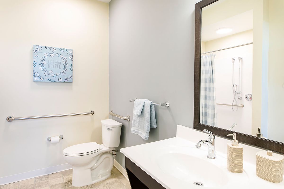 A minimalist bathroom with a white sink, toilet, and a large mirror.