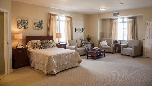 A spacious and inviting bedroom area featuring a comfortable bed, seating, and soft natural lighting.