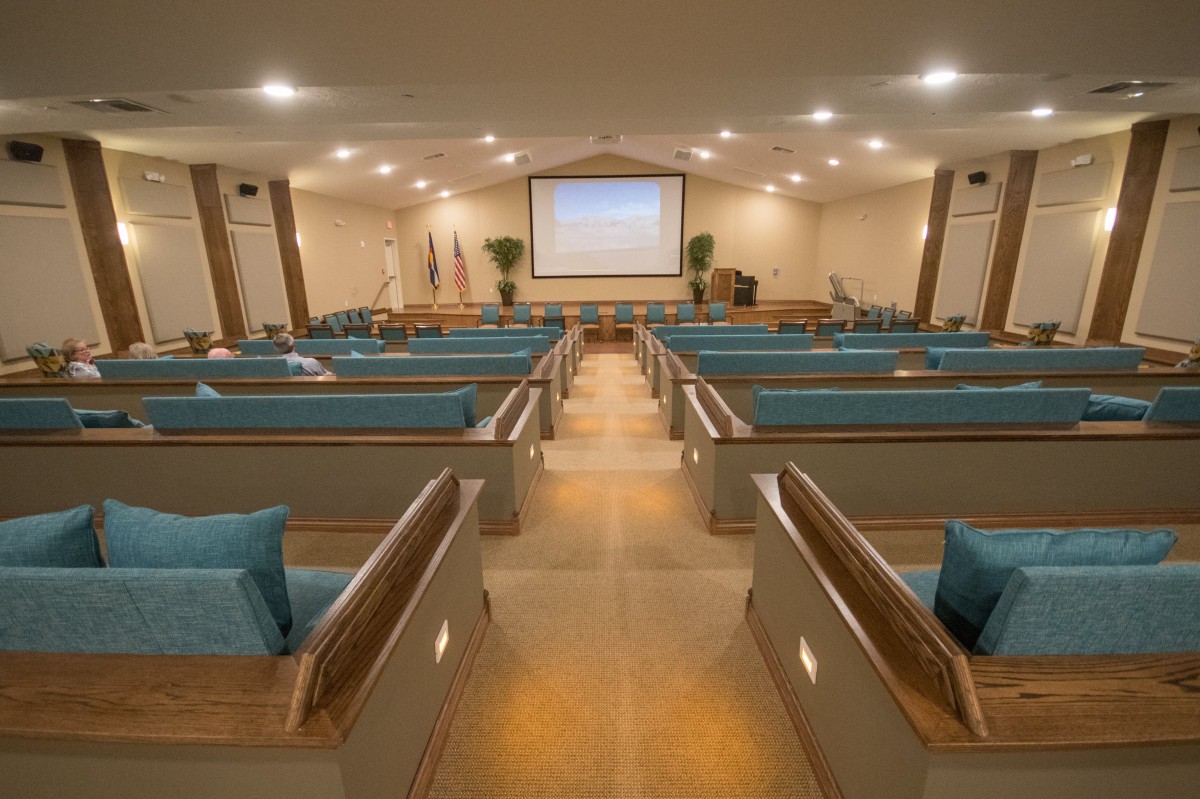 An interior view of a church with rows of pews and a large projection screen at the front.
