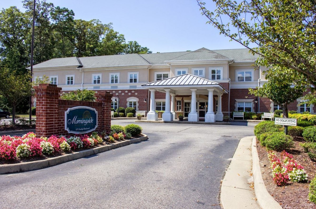 A well-maintained building entrance with a driveway and landscaped garden.