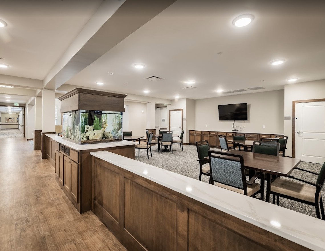 A modern dining area with an aquarium, featuring wooden furniture and flooring.