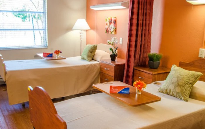 A cozy bedroom with twin beds, decorated with flowers and a warm lamp.