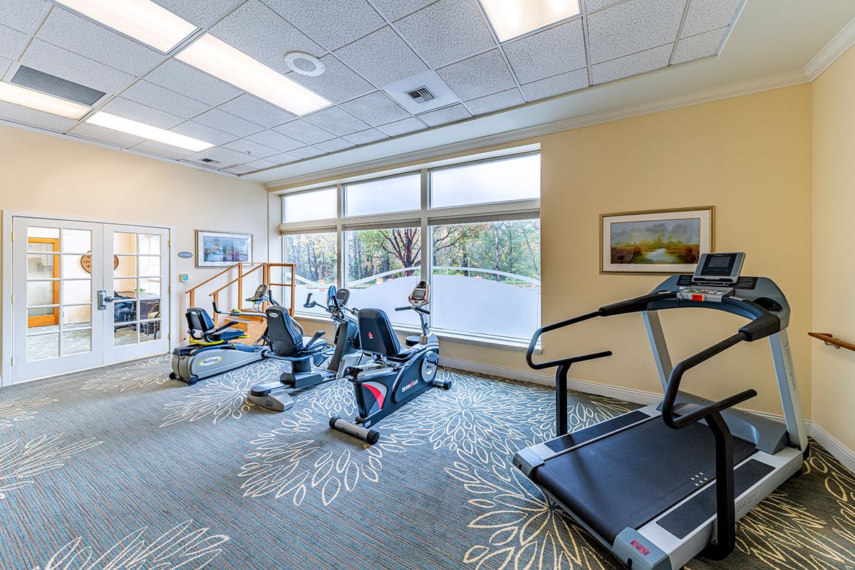 A well-lit gym with exercise equipment including treadmills and stationary bikes.
