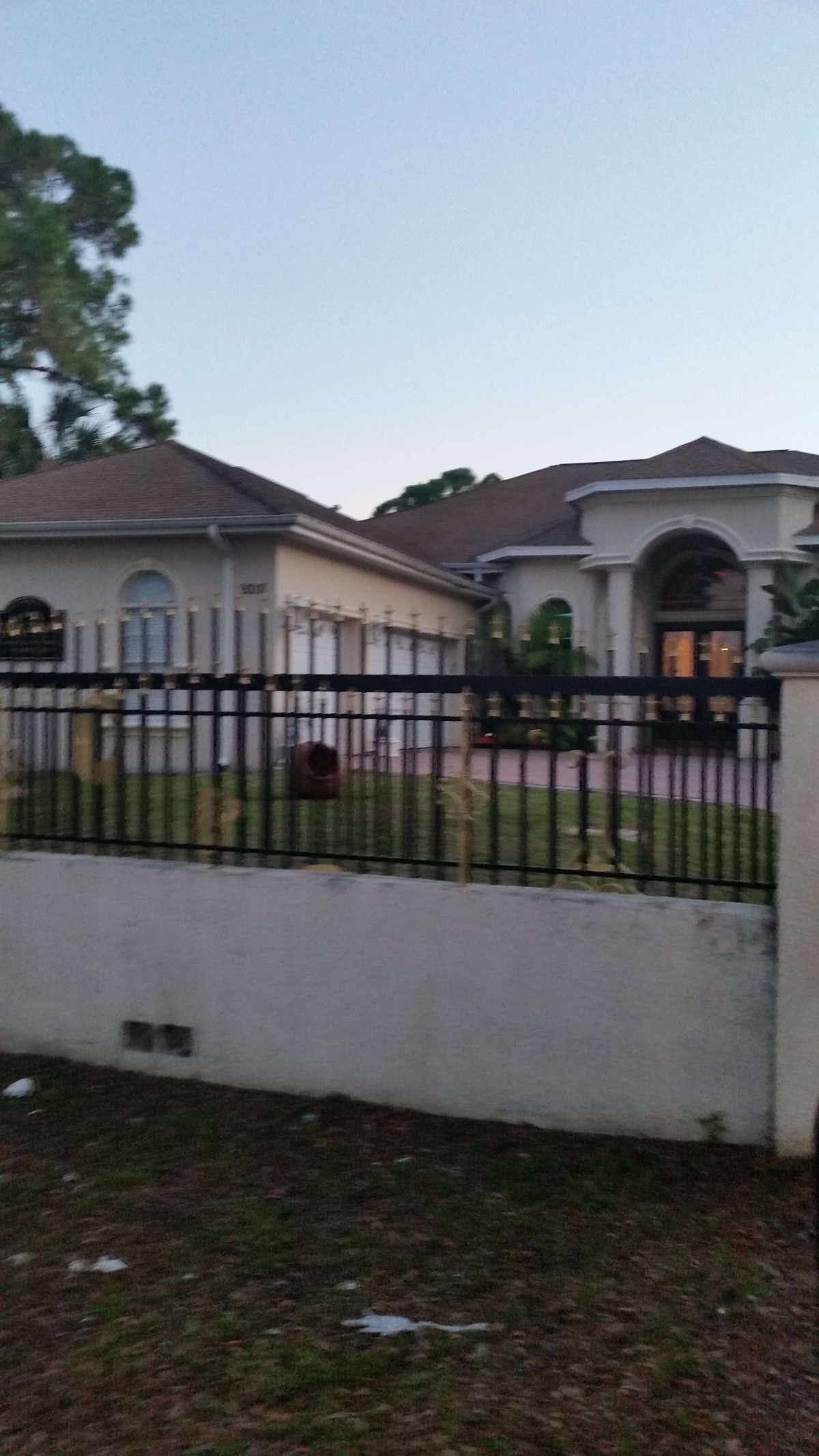 A view of a large residential house with a fenced yard.