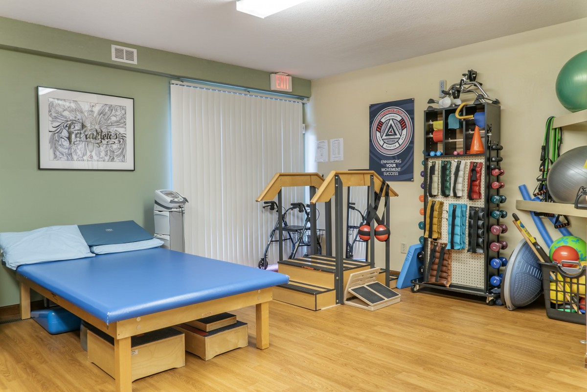 A well-equipped physical therapy room with a treatment table and exercise equipment.