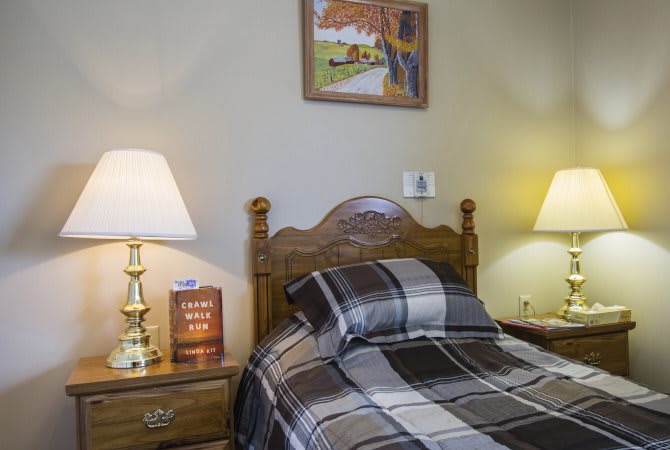 A cozy bedroom with a wooden headboard, plaid bedding, and lamps on the nightstands.