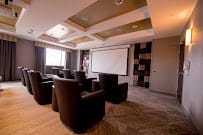 A modern conference room equipped with comfortable seating and a projector screen.