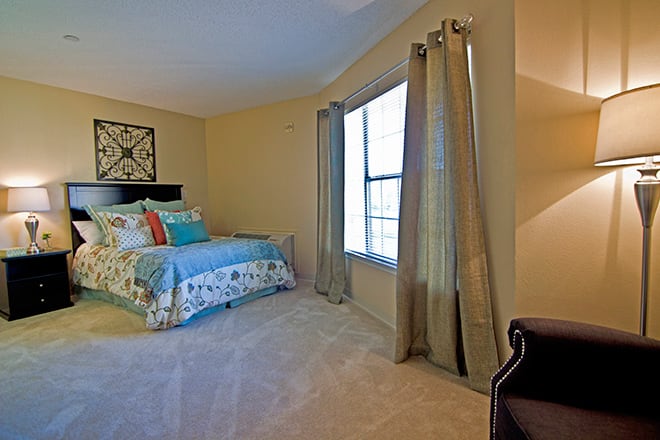 A cozy bedroom with a colorful bedspread and large window.