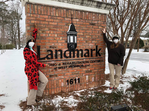 Visitors posing by the Landmark sign in a snowy setting.