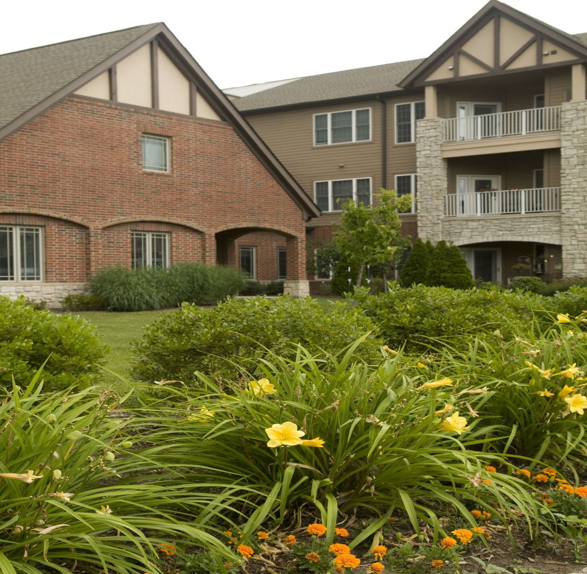 A well-maintained apartment building with lush landscaping and blooming flowers in the foreground.