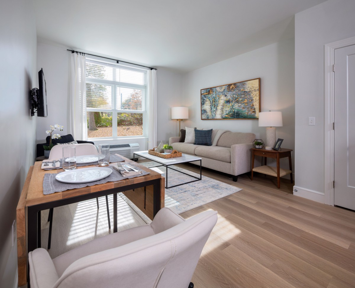 A modern living room with a dining area, featuring comfortable seating and ample natural light.