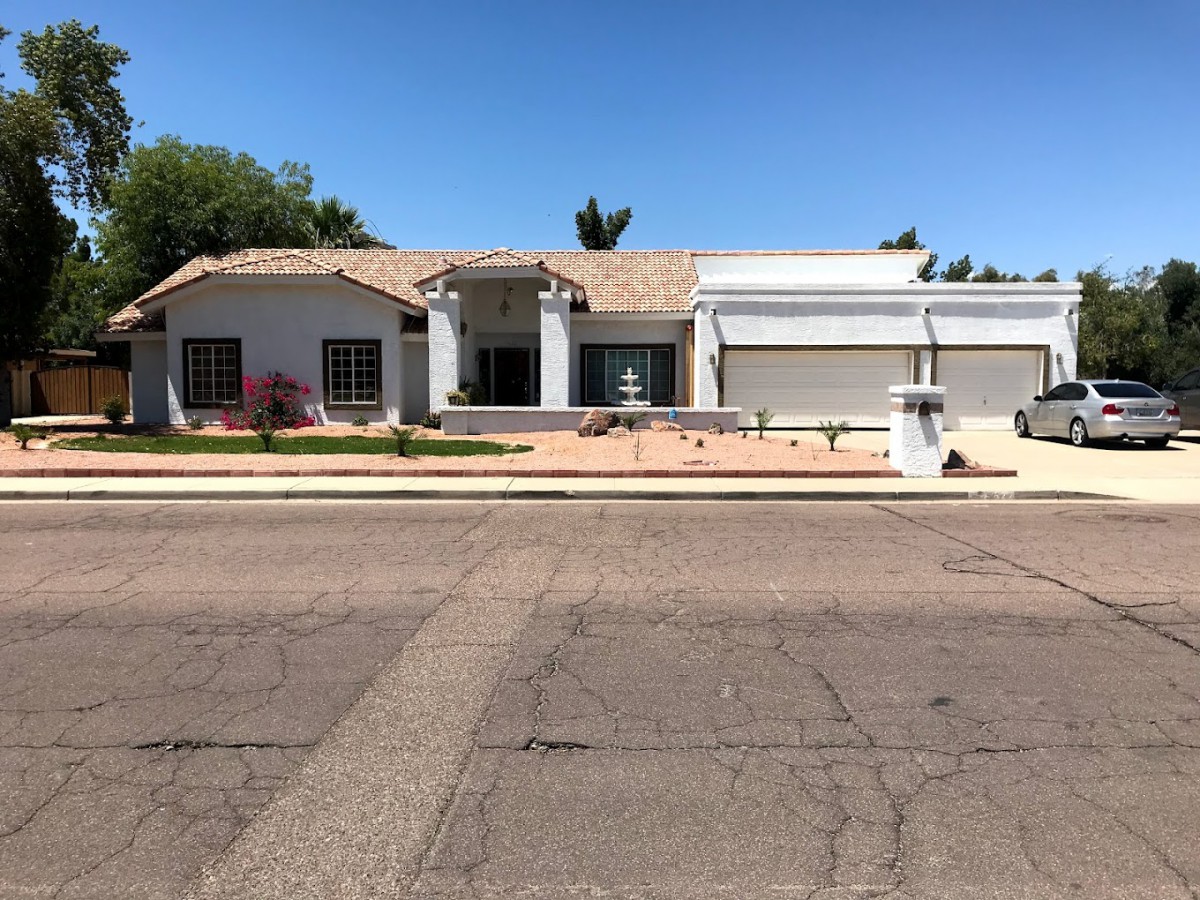 A suburban house with a well-maintained front yard and a two-car garage under a clear blue sky.