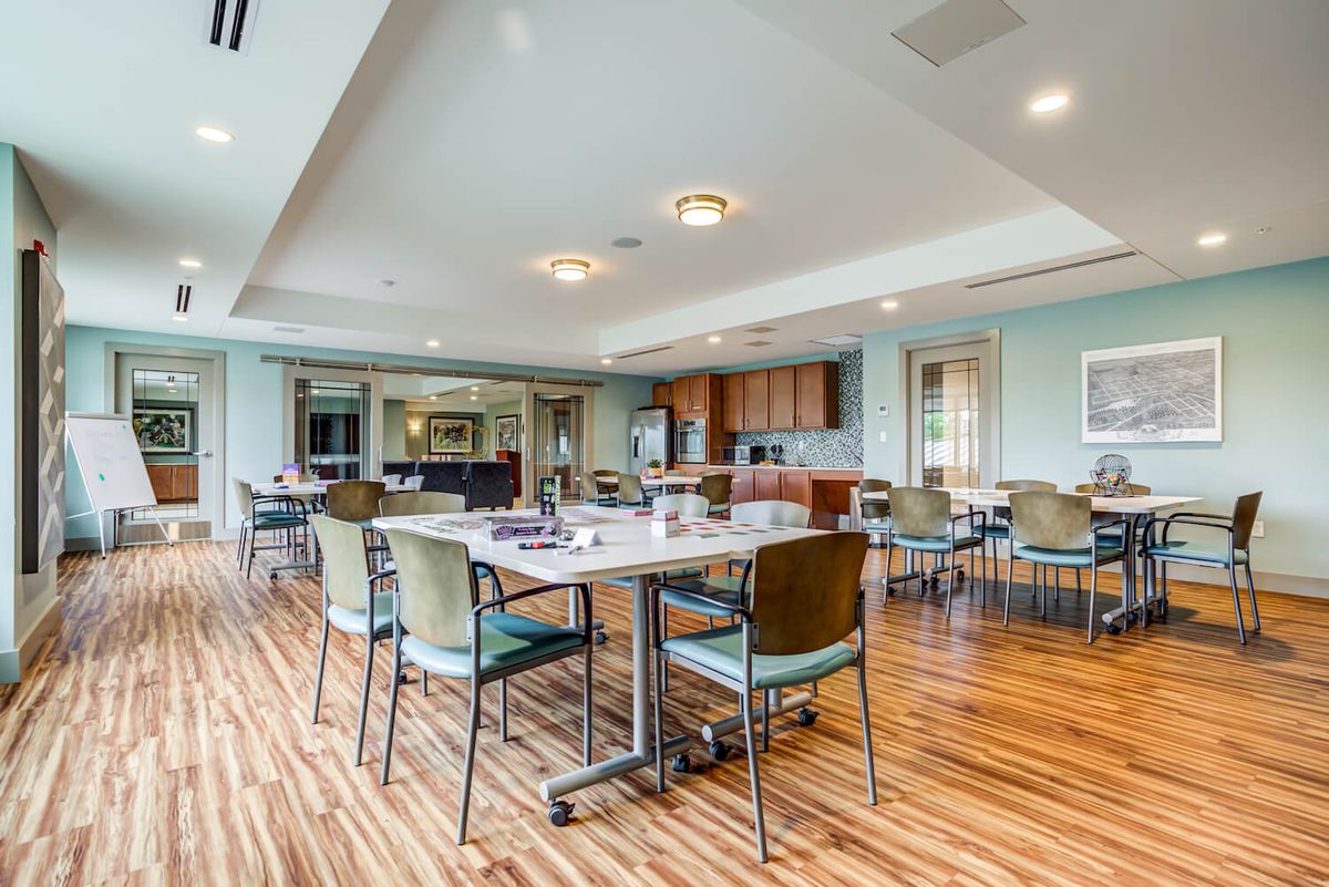 A modern and spacious dining area with wooden flooring and well-arranged tables and chairs.