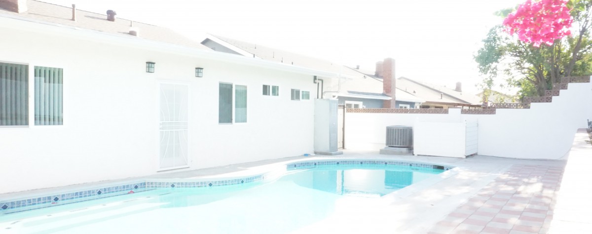 A backyard with a swimming pool and a house in the background.