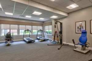 A well-lit gym with treadmills and other exercise equipment.