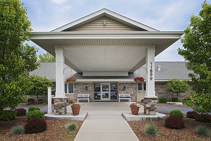 The entrance of a building with a covered walkway and neatly arranged landscaping.