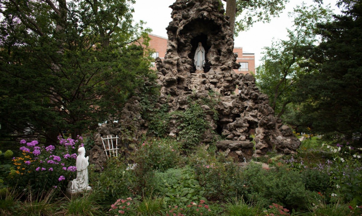 A serene outdoor grotto featuring statues and lush greenery.