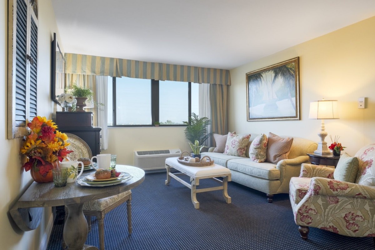 A cozy living room with a comfortable sofa, coffee table, and large windows bringing in natural light.