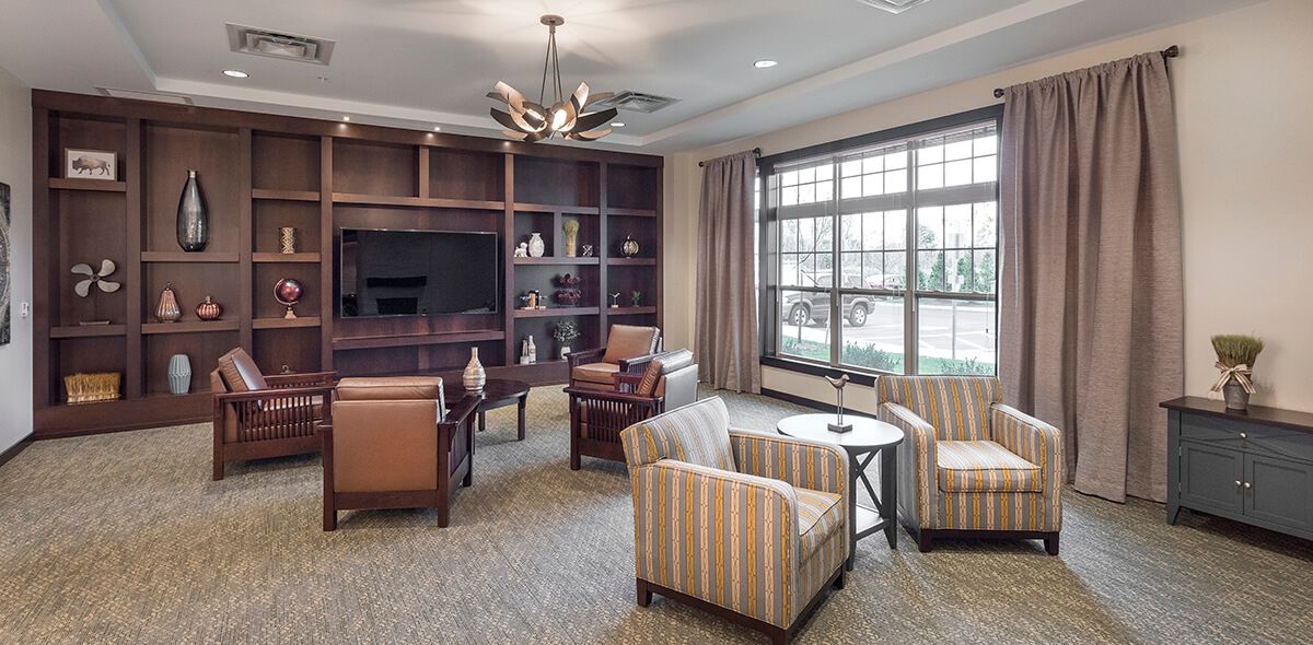 A cozy living room with comfortable seating, a large window, and bookshelves.