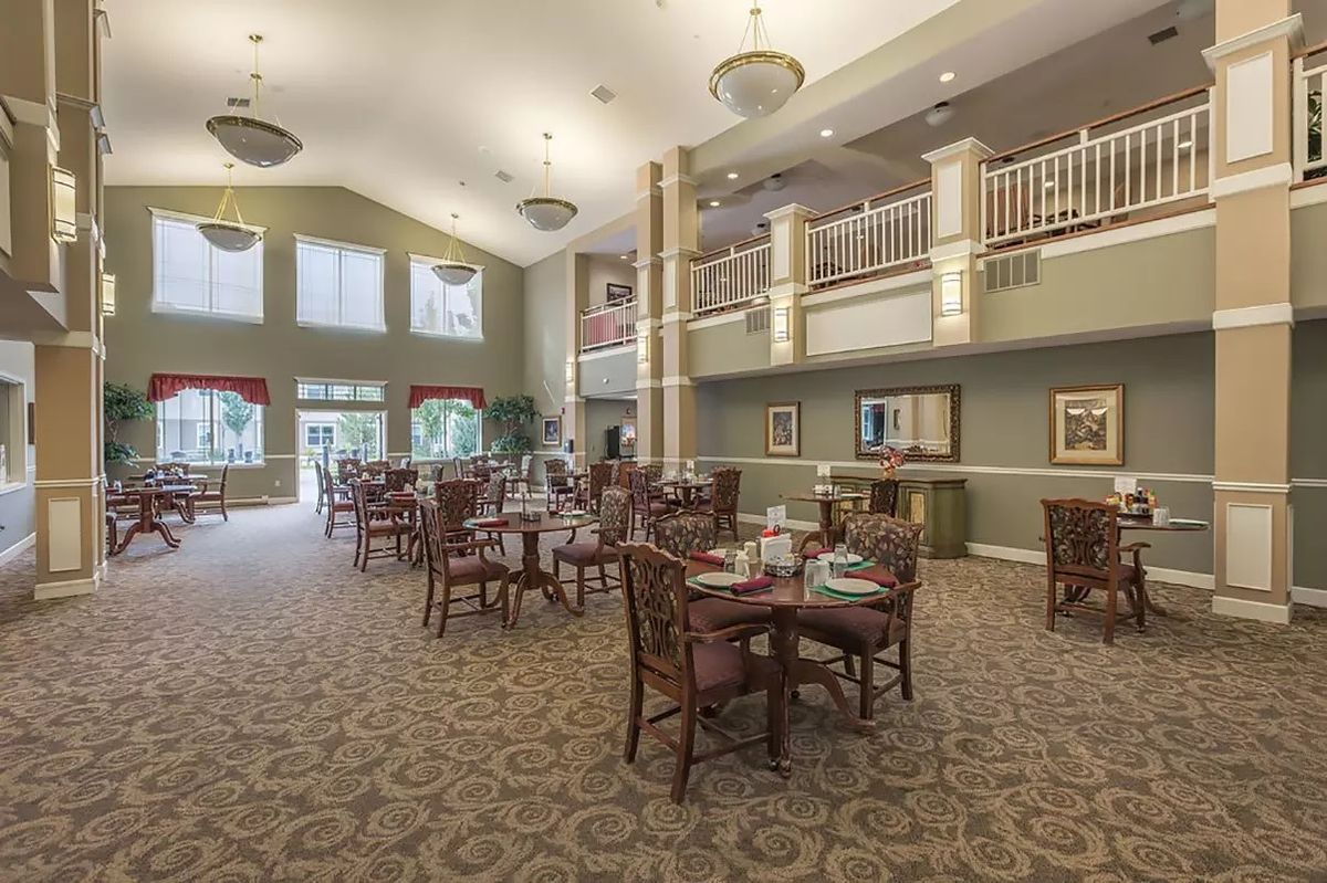 A spacious and elegantly decorated dining area with tables and chairs under a high ceiling.