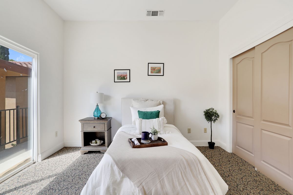 A minimalist bedroom with a single bed and nightstand, featuring clean white walls and simple decor.