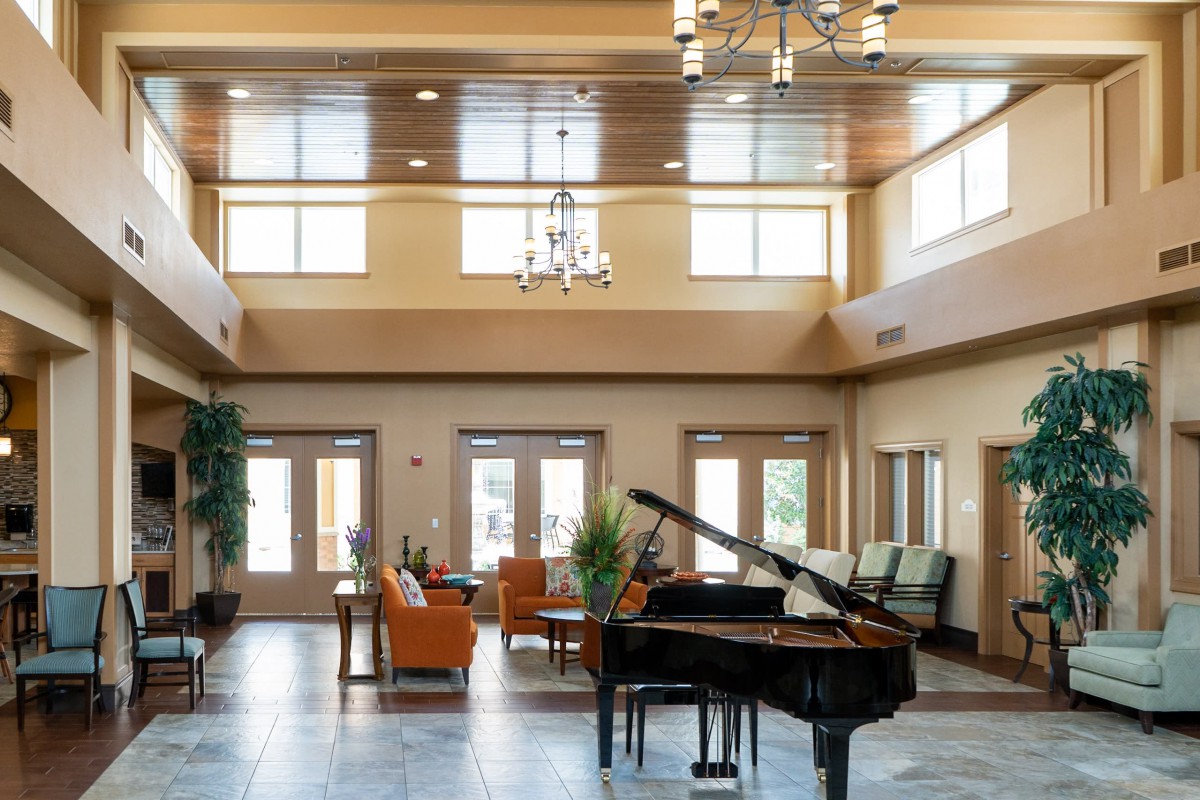 A spacious lobby with a grand piano, cozy seating area, and abundant natural light.