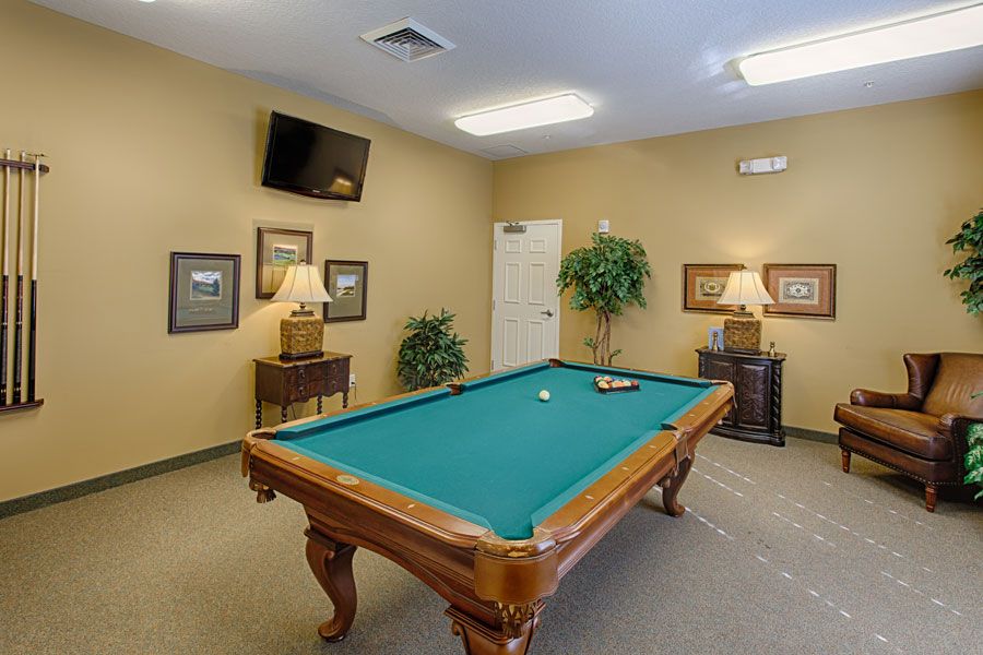 A cozy game room featuring a billiards table and wall-mounted television, complemented by warm decor.