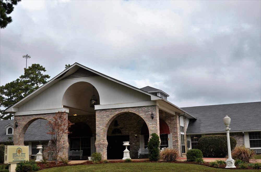 A brick house with arched entryways and a well-maintained front yard under a cloudy sky.