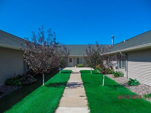 A well-maintained courtyard with a central pathway, surrounded by residential buildings and lush greenery.