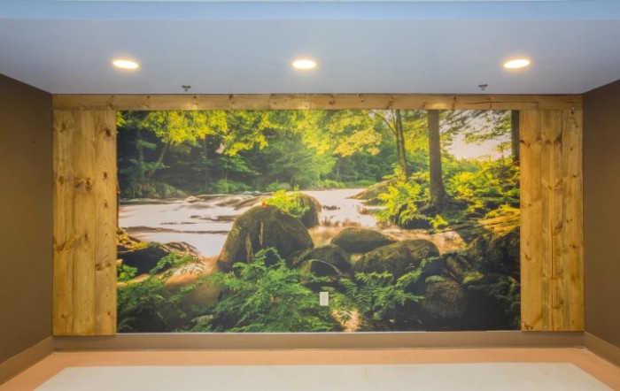 A mural depicting a serene forest landscape with a river flowing among rocks and lush greenery.