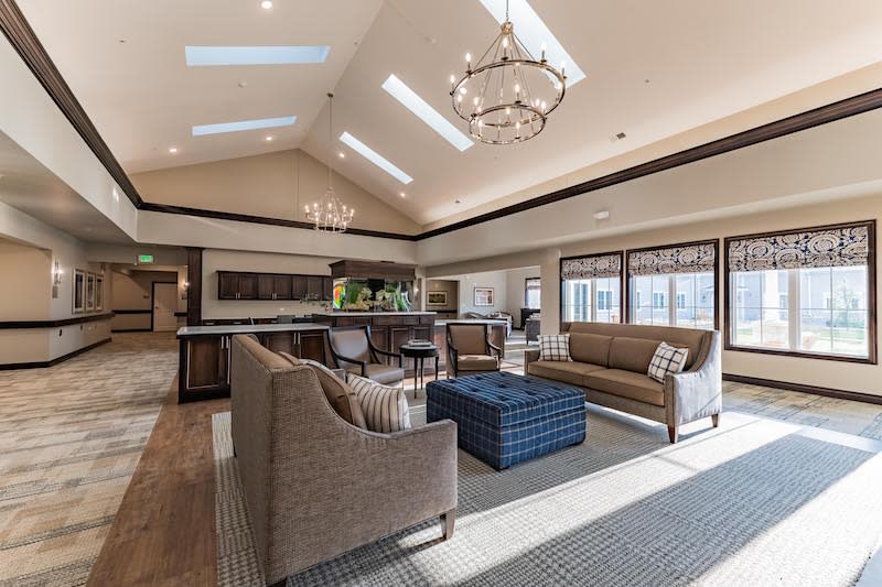 A spacious and modern living room with elegant furniture, skylights, and a large chandelier.