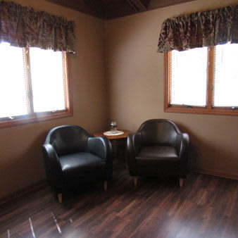 A cozy corner with two leather chairs and a small table by the window.