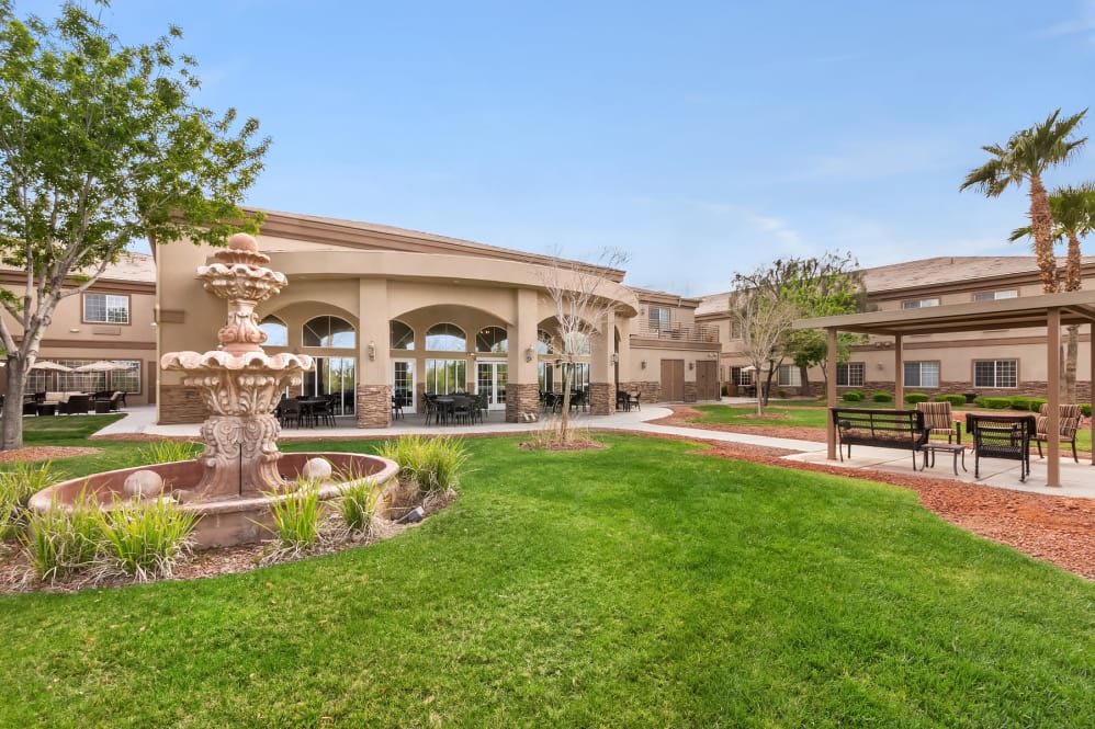 A large building with a beautifully landscaped lawn, featuring a fountain and a pathway.