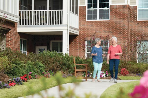 Two elderly women enjoying a leisurely walk in their community garden.