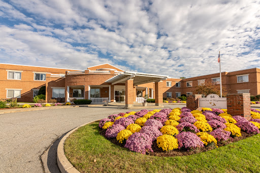 A welcoming healthcare facility surrounded by vibrant flowers and a picturesque cloudy sky.